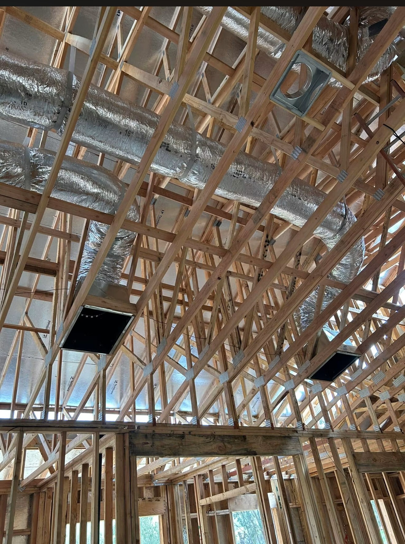 New ductwork and insulation run through attic framing during new construction