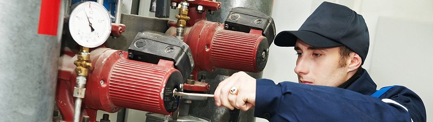 Technician servicing a boiler and pump system