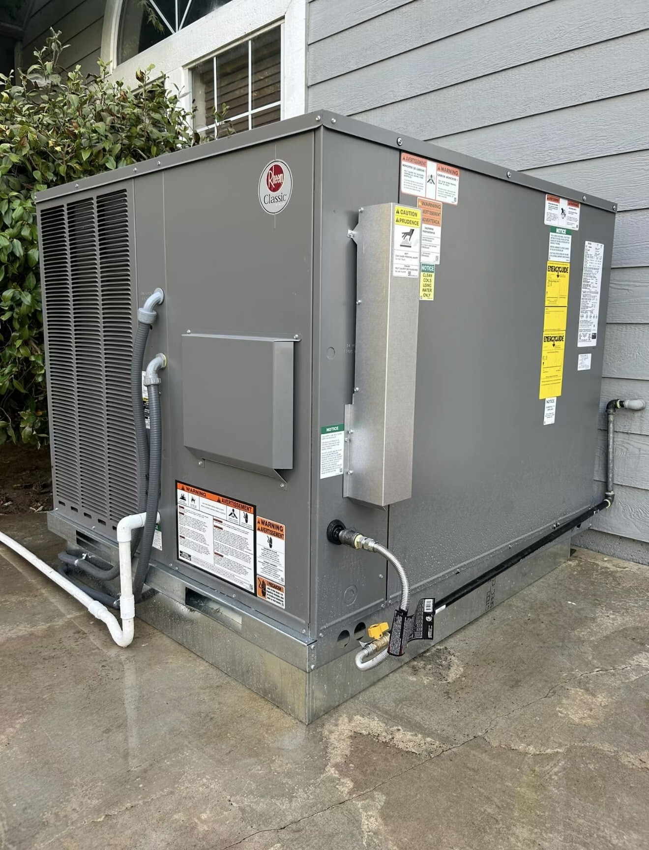 New Rheem package HVAC unit installed beside a home
