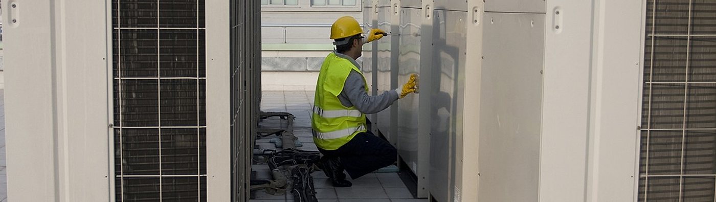 Technician servicing commercial rooftop AC units