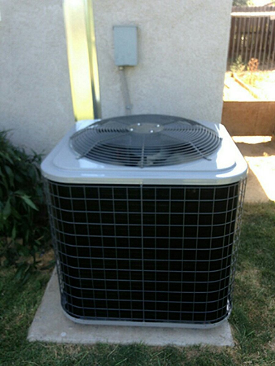 Residential split-system AC condenser installed beside a home